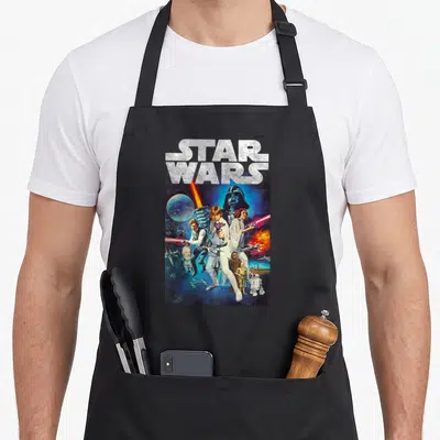 Hope distressed apron - STAR WARS logo above vintage photo montage of Luke Skywalker and space elements in blue and red — shown on a black cotton canvas apron against a white background