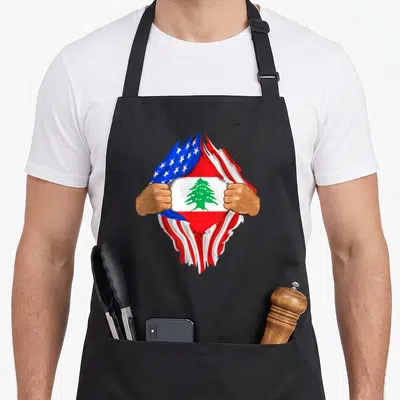Lebanese blood apron - Two hands tear USA flag to reveal Lebanese flag with green cedar tree — shown on a black cotton canvas apron against a white background