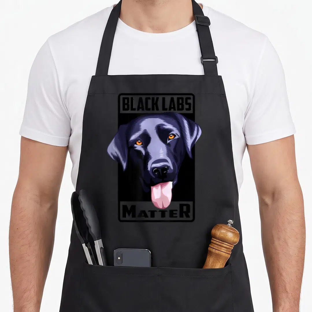 Matter lab apron - Cartoon black labrador head between BLACK LABS and MATTER banners with pink tongue — shown on a black cotton canvas apron against a white background