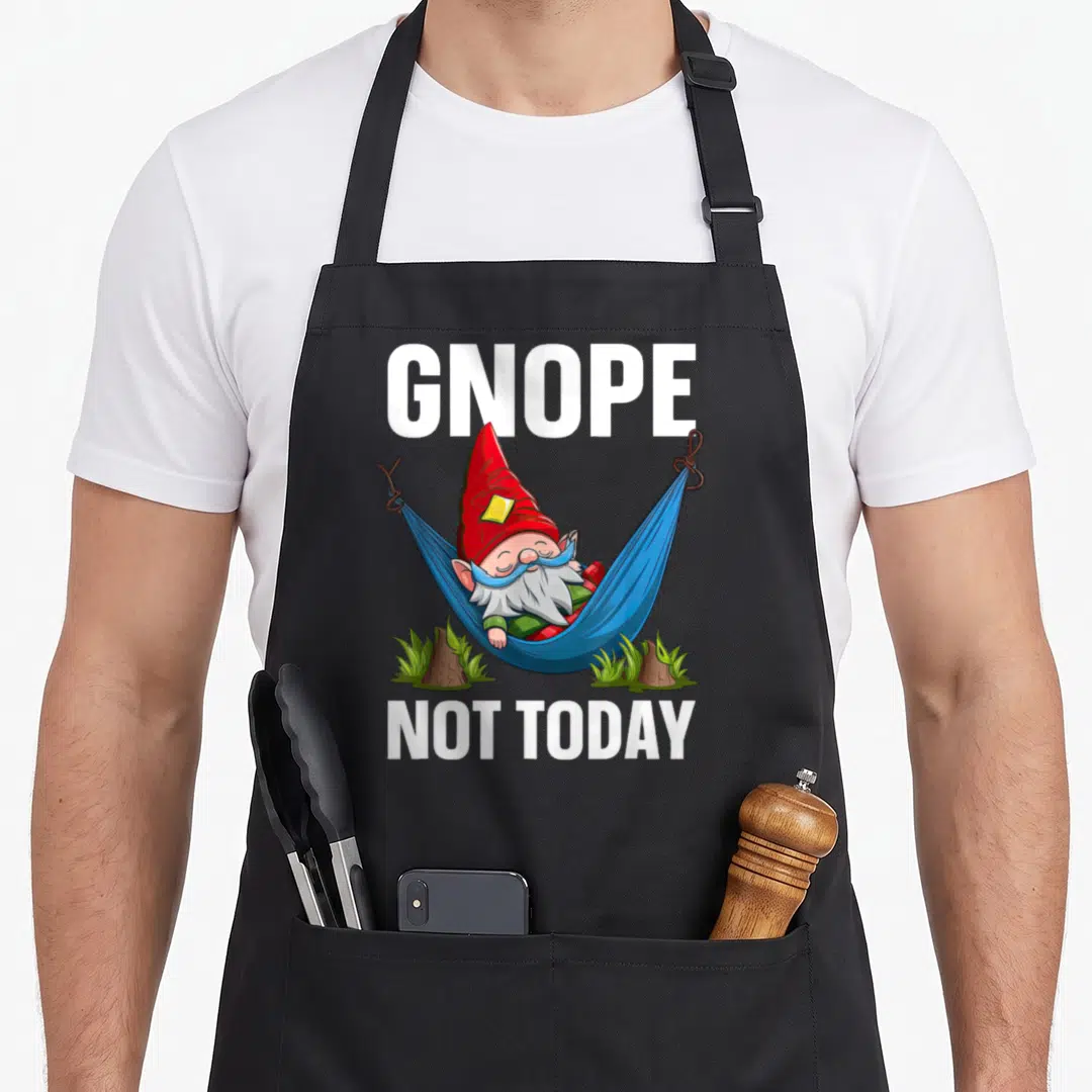 Gnome whimsical aprons - Gnope Not Today gnome lying in blue hammock with white text — shown on a black cotton canvas apron against a white background