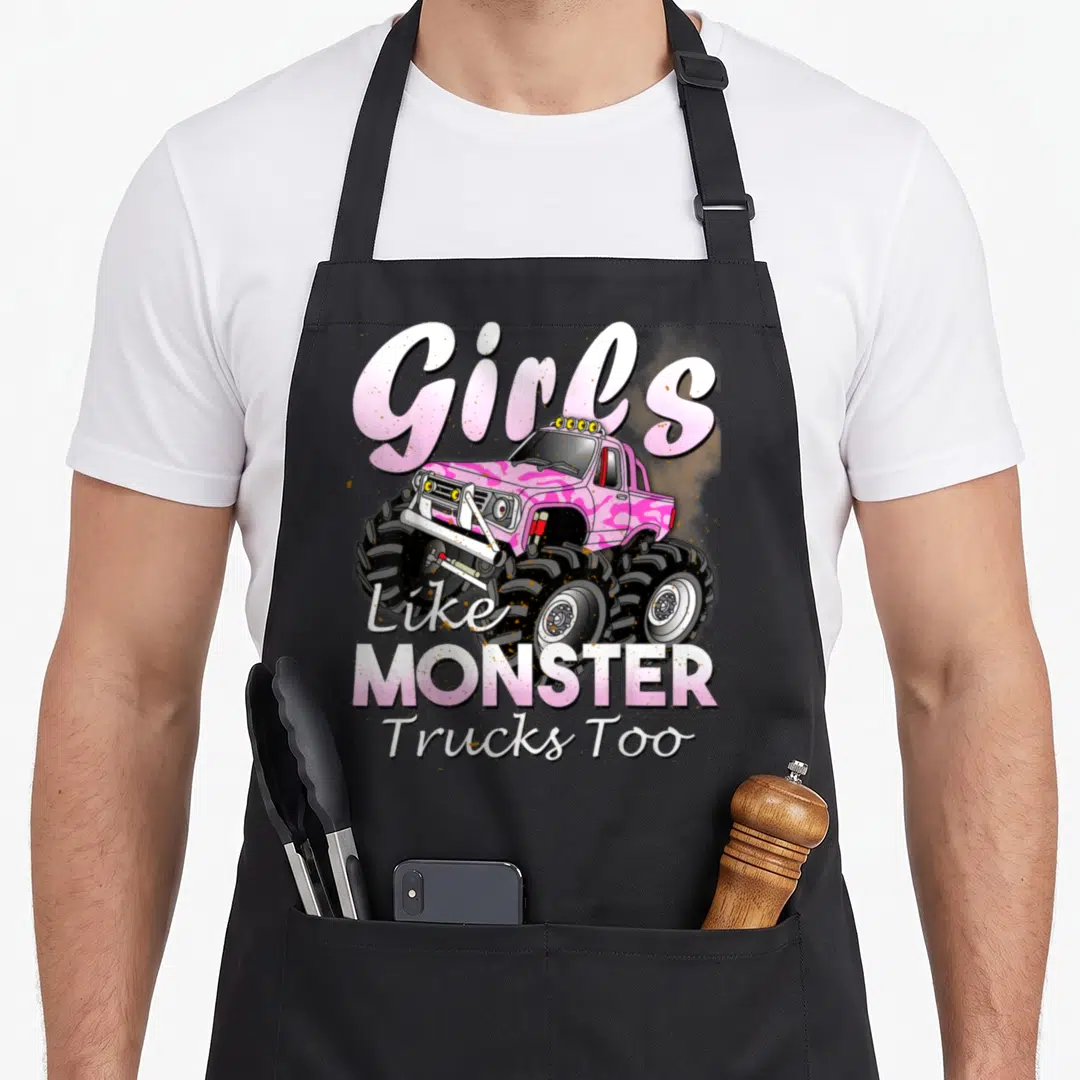 Birthday truck aprons - Pink monster truck cartoon with Girls Like MONSTER Trucks Too text — shown on a black cotton canvas apron against a white background