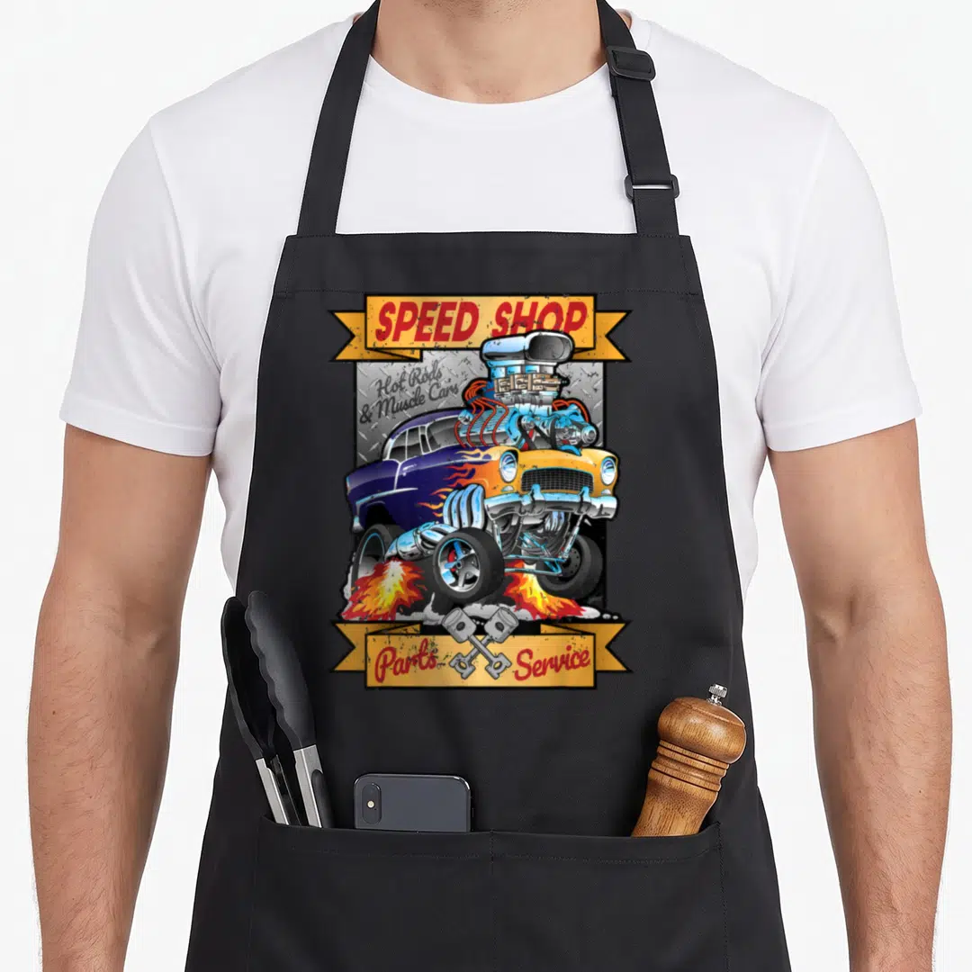 Speed cartoon apron - Blue and yellow hot rod with massive engine, crossed pistons, and speed shop text on yellow — shown on a black cotton canvas apron against a white background