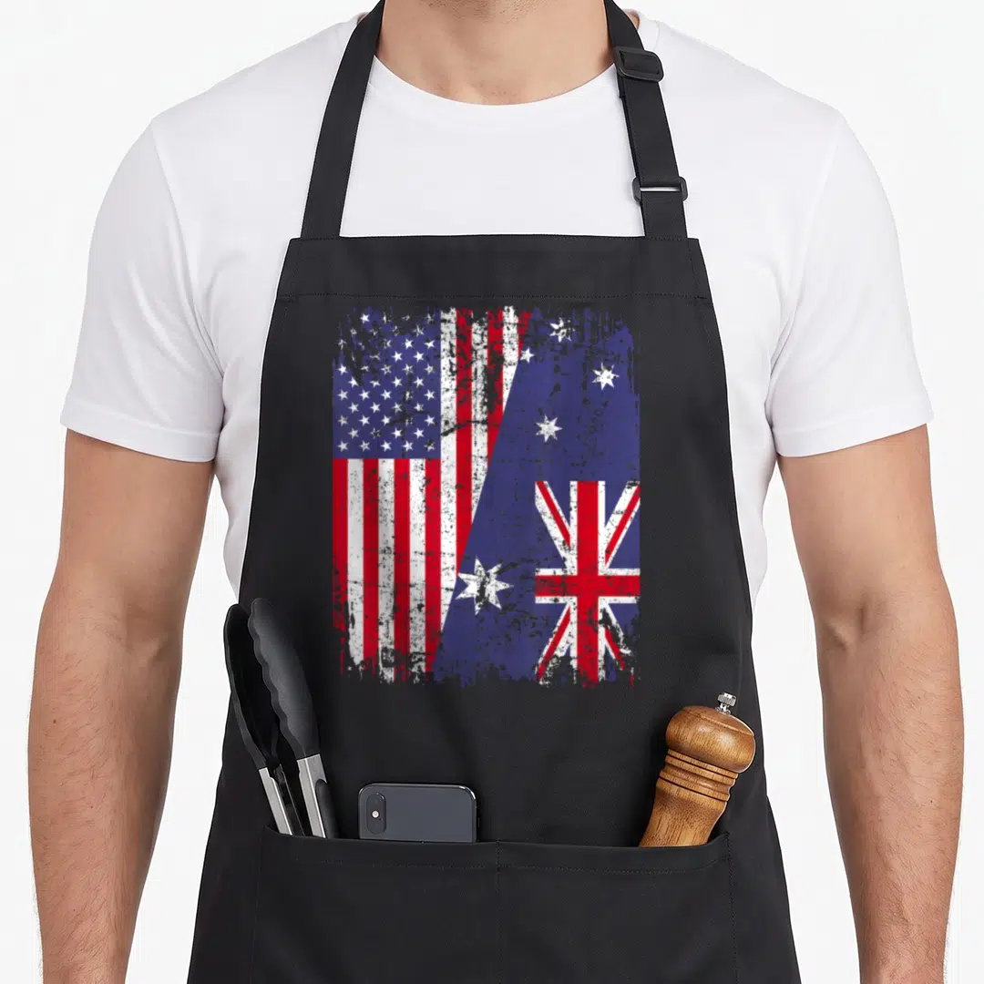 Root australian apron - Merged USA and Australian flags in red white blue distressed style — shown on a black cotton canvas apron against a white background