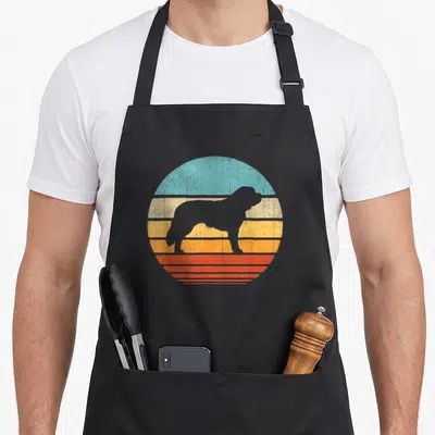 Bernard 60s dog apron - Retro Saint Bernard silhouette over blue yellow orange and red horizontal sunset stripes — shown on a black cotton canvas apron against a white background