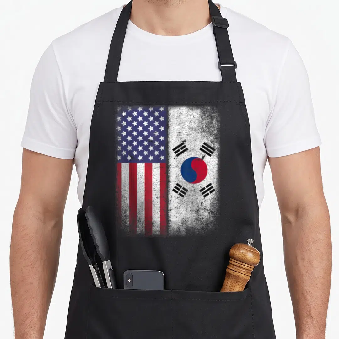 South american flag apron - Distressed US and South Korean flags side by side in red white blue and black — shown on a black cotton canvas apron against a white background