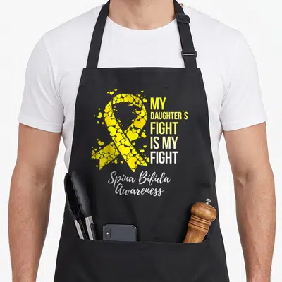 Daughter spina bifida awareness apron - Yellow ribbon composed of hearts with stacked text reading My Daughter's Fight — shown on a black cotton canvas apron against a white background