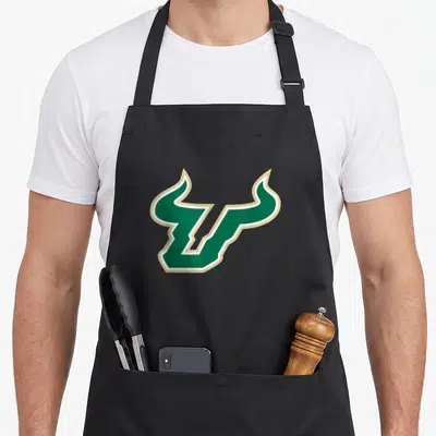 South bull florida apron - Stylized green U with horns outlined in white and gold — shown on a black cotton canvas apron against a white background