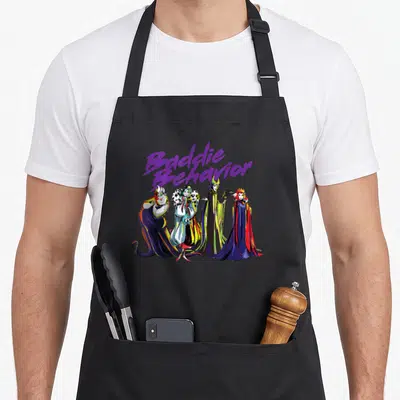 Baddie novelty apron - Purple Baddie Behavior text above four female villains and a perched raven in cartoon style — shown on a black cotton canvas apron against a white background