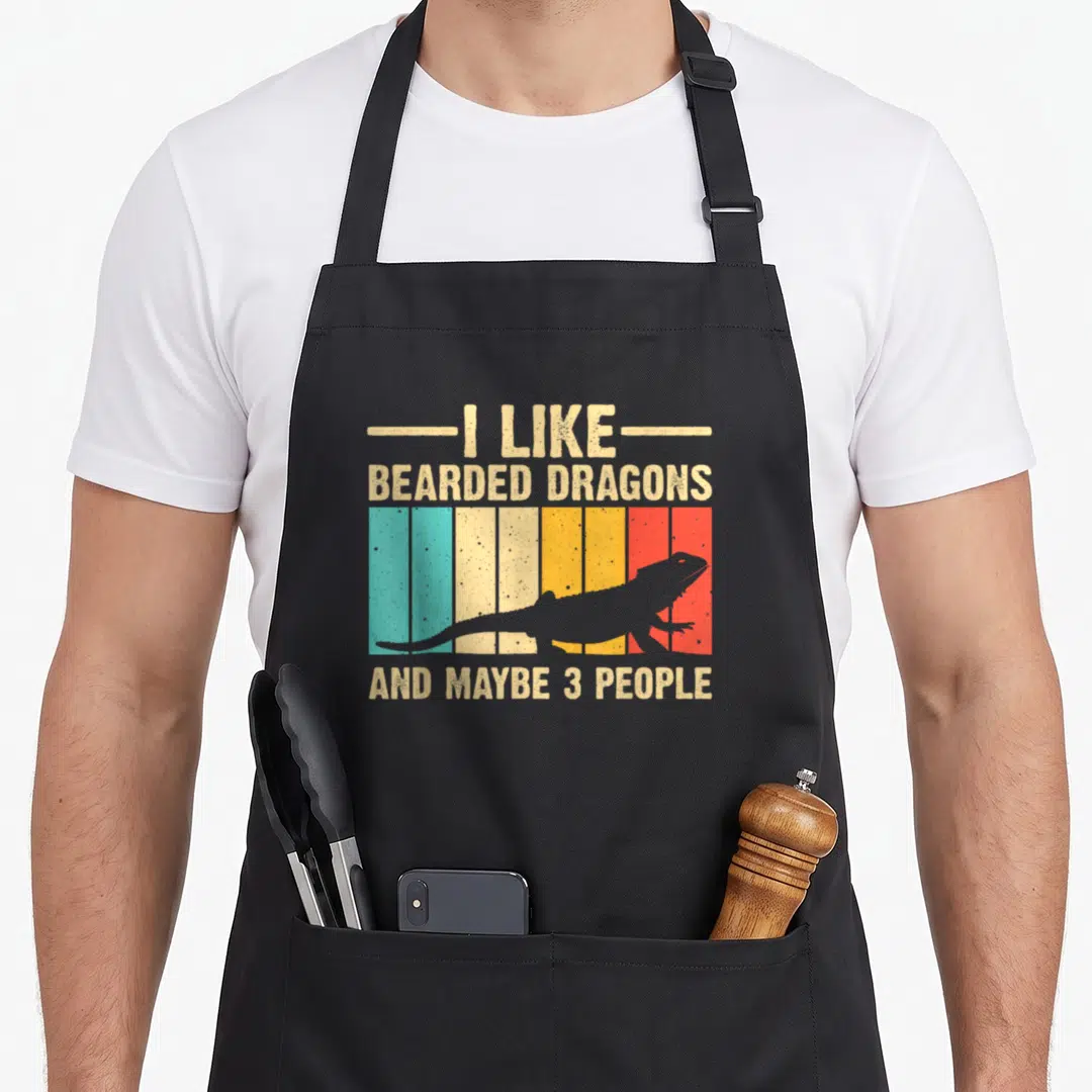 Bearded pogona dragon apron - Retro striped bearded dragon silhouette with sarcastic text I LIKE BEARDED DRAGONS — shown on a black cotton canvas apron against a white background
