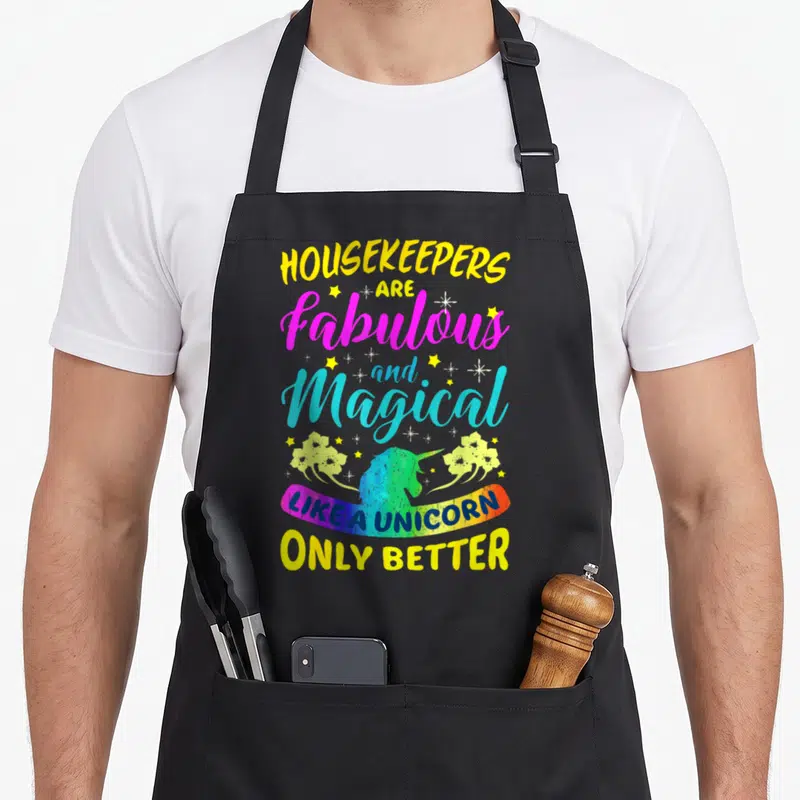 Colourful housekeeper apron - Stacked text Housekeepers Are Fabulous and Magical Like A Unicorn Only Better — shown on a black cotton canvas apron against a white background