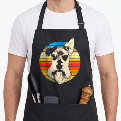 Standard miniature schnauzer apron - Retro stylized dog head with one upright ear against a striped blue orange — shown on a black cotton canvas apron against a white background