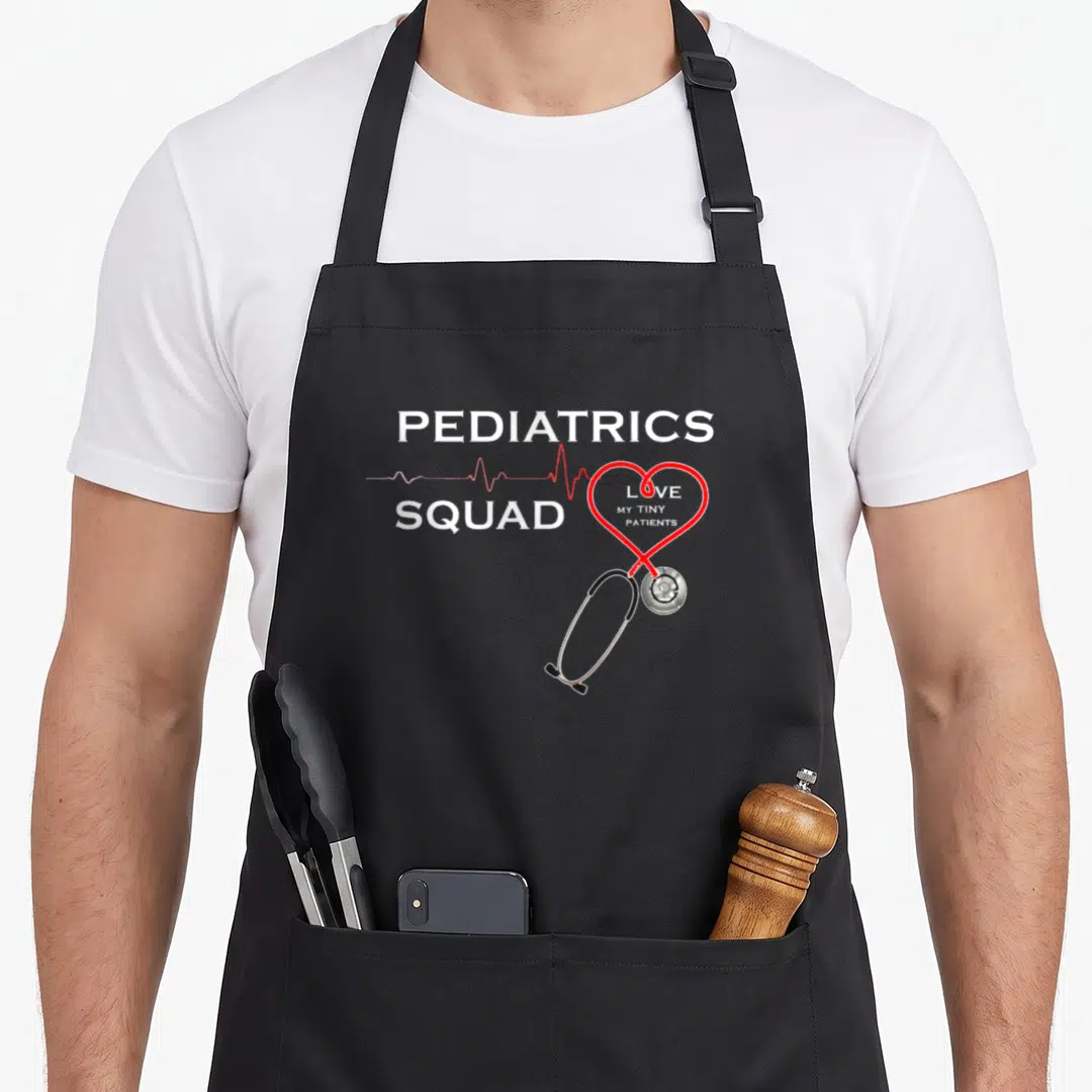 Squad nurse apron - PEDIATRICS SQUAD text with stethoscope heart and heartbeat line in white red black — shown on a black cotton canvas apron against a white background
