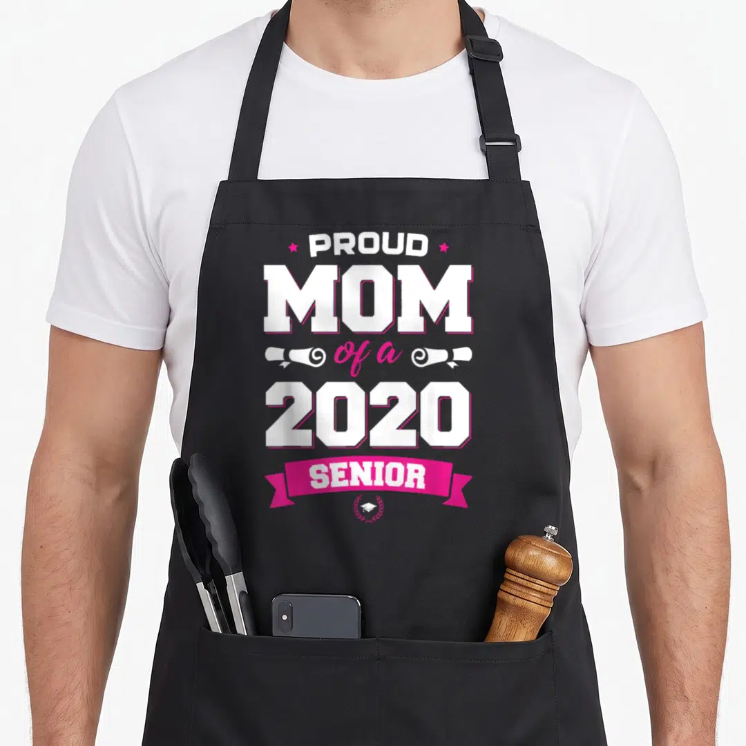 Proud class senior apron - Stacked text proud mom 2020 senior with pink ribbon and graduation cap icon — shown on a black cotton canvas apron against a white background