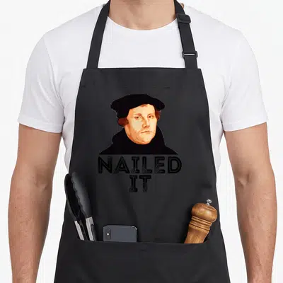 Protestant nailed it aprons - Retro portrait of a man in a black hat with bold NAILED IT text below — shown on a black cotton canvas apron against a white background