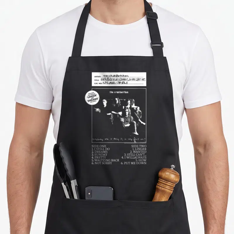 Cranberry vinyl apron - Black and white band photo with tracklist and handwritten slogan on black bib — shown on a black cotton canvas apron against a white background