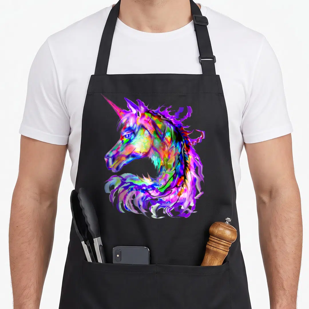 Unicorn kawaii apron - Multicolored unicorn head facing left in purple blue pink yellow green cartoon art — shown on a black cotton canvas apron against a white background
