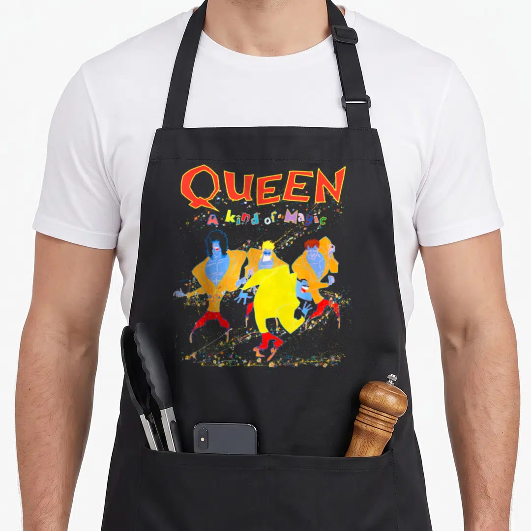 Kind magic apron - Four blue figures in yellow jackets and red pants dancing under QUEEN text with confetti — shown on a black cotton canvas apron against a white background