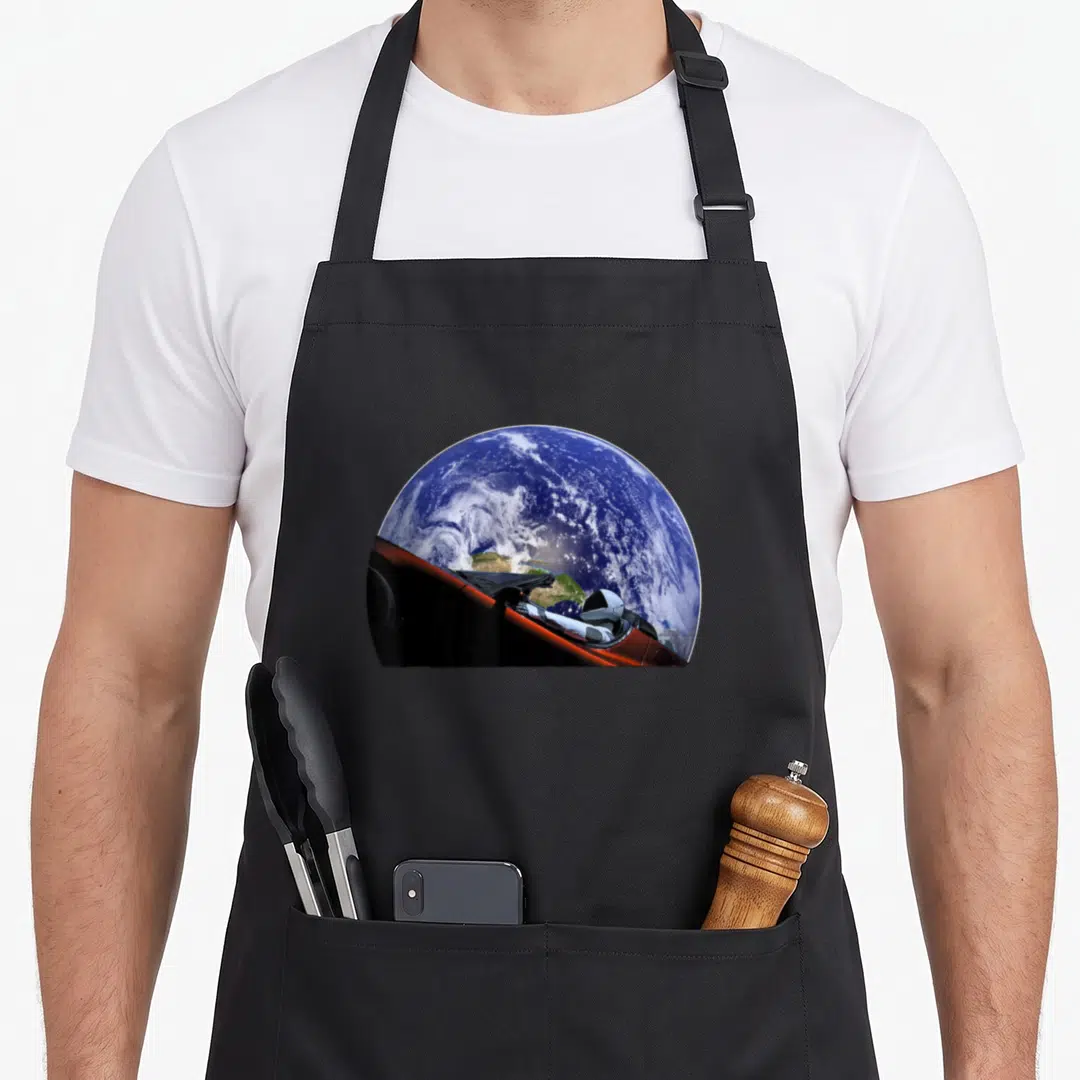 Starman space city company apron - Photo of Earth and astronaut in red spacecraft floating in space — shown on a black cotton canvas apron against a white background