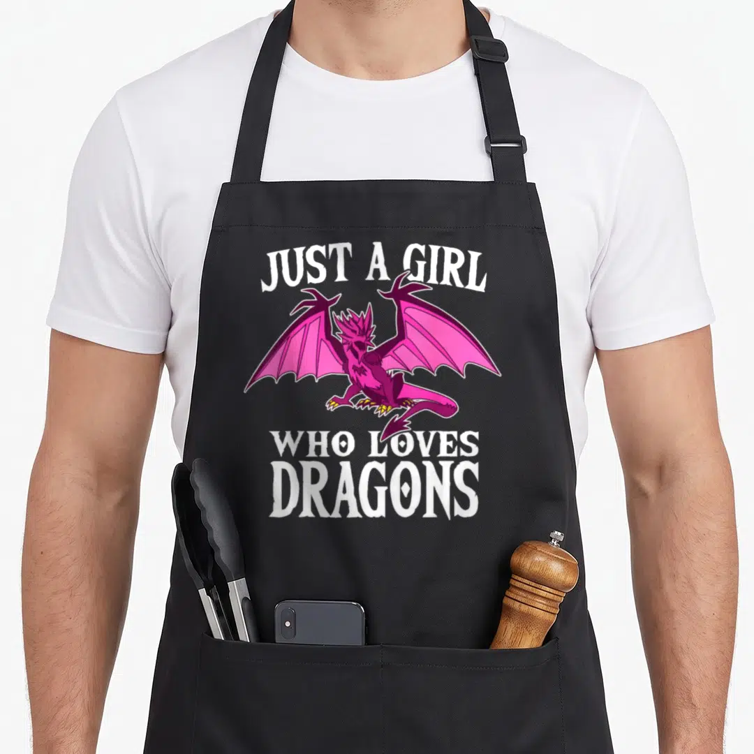 Funny costume dragon apron - Pink and purple cartoon dragon surrounded by white text Just A Girl Who Loves Dragons — shown on a black cotton canvas apron against a white background