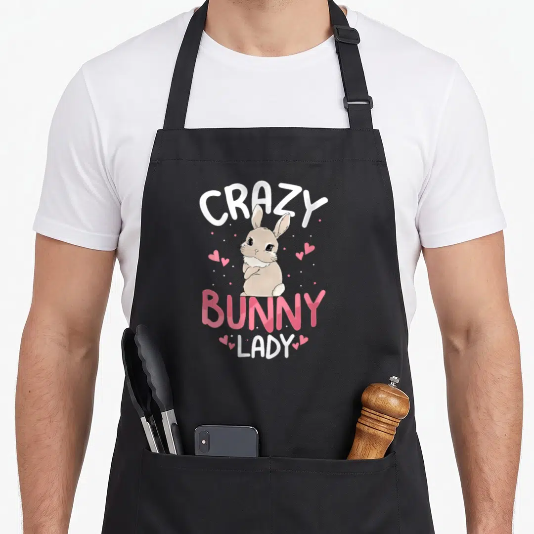 Cool rabbit animal bunny apron - Beige cartoon bunny between white Crazy and pink Bunny Lady text with scattered hearts — shown on a black cotton canvas apron against a white background