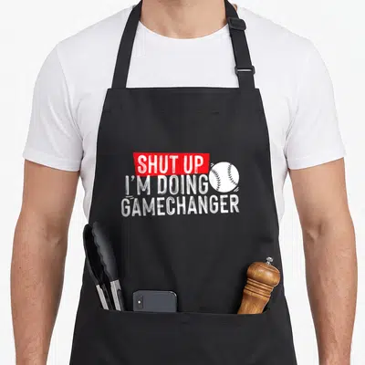 Shut baseball apron - White text SHUT UP in red box next to baseball illustration — shown on a black cotton canvas apron against a white background