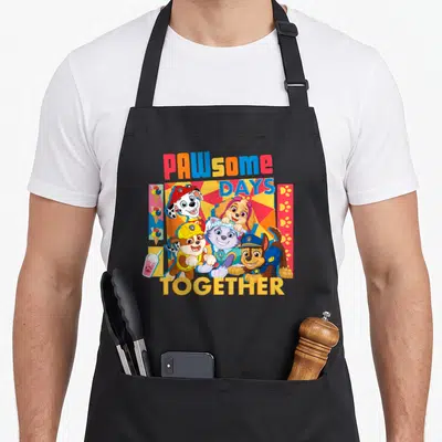 Pawsome novelty apron - Four cartoon puppies with ice cream cones and paw prints under PAWsome DAYS TOGETHER text — shown on a black cotton canvas apron against a white background