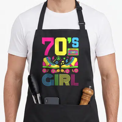 70s chef outfit apron - Retro 70S GIRL print with pink yellow blue green roller skates and cassette tape — shown on a black cotton canvas apron against a white background