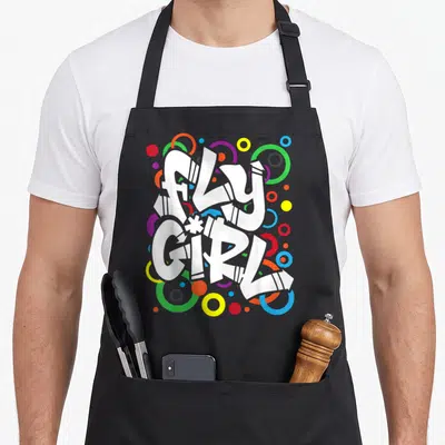 80s hip apron - FLY GIRL white graffiti text surrounded by red blue yellow green purple circles — shown on a black cotton canvas apron against a white background