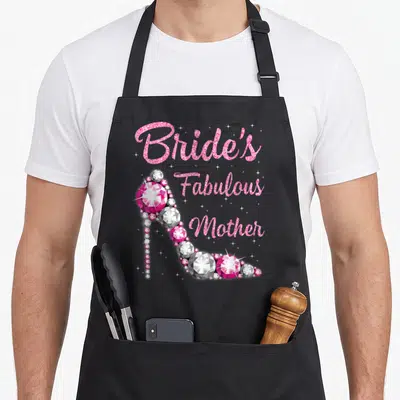 Mother wedding day aprons - Bride's Fabulous Mother text beside pink and grey gemstone high heel shoe — shown on a black cotton canvas apron against a white background