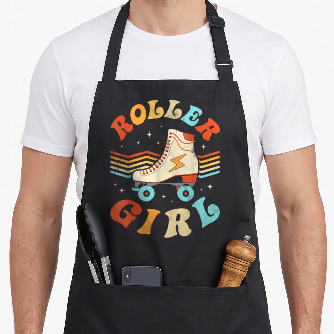 Skater 70s apron - Retro roller skate with ROLLER GIRL text in orange yellow beige and light blue — shown on a black cotton canvas apron against a white background