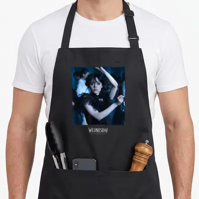 Wednesday queen apron - Square photo of Wednesday Addams dancing in blue tones with WEDNESDAY text below — shown on a black cotton canvas apron against a white background