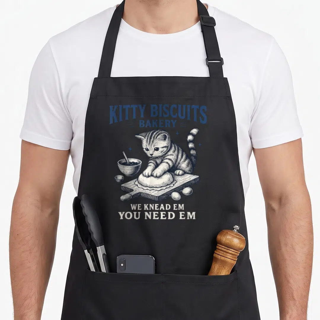 Bakery kitty cat apron - Blue and white line art of a kitten kneading dough with bakery text — shown on a black cotton canvas apron against a white background
