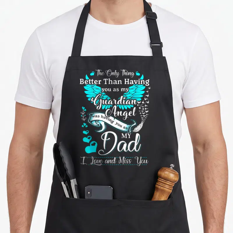Missing angels and aprons - Cyan angel wings with white ribbon and text reading Better Than Having you as my Guardian — shown on a black cotton canvas apron against a white background