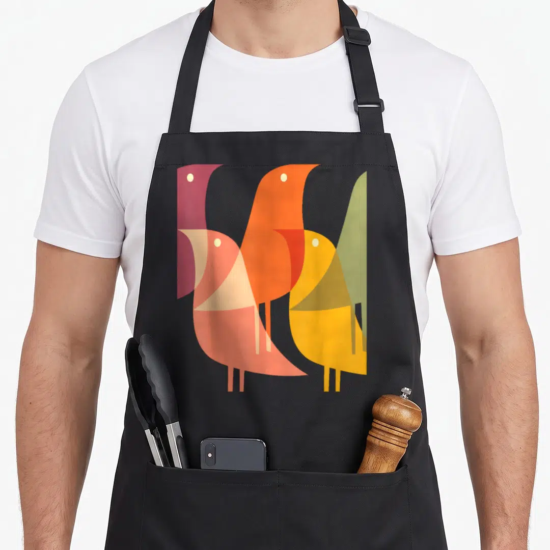 Deco bird apron - Four overlapping geometric birds in purple orange yellow and green — shown on a black cotton canvas apron against a white background