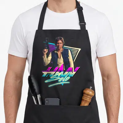 Neon eighty and awesome apron - Man holding blaster with HAN Solo text on retro geometric background in purple and cyan — shown on a black cotton canvas apron against a white background