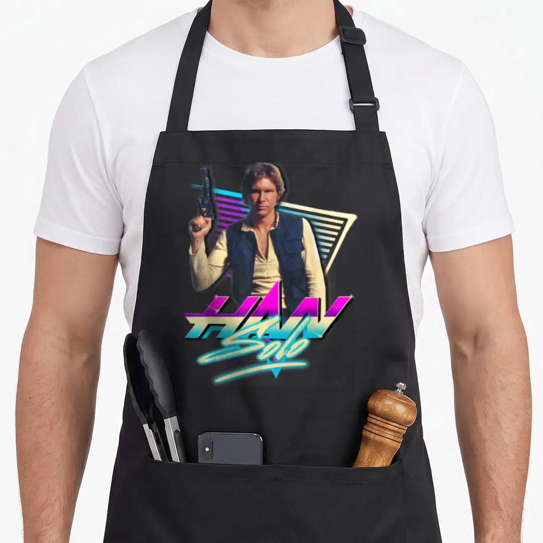 Neon eighty and awesome apron - Man holding blaster with HAN Solo text on retro geometric background in purple and cyan — shown on a black cotton canvas apron against a white background