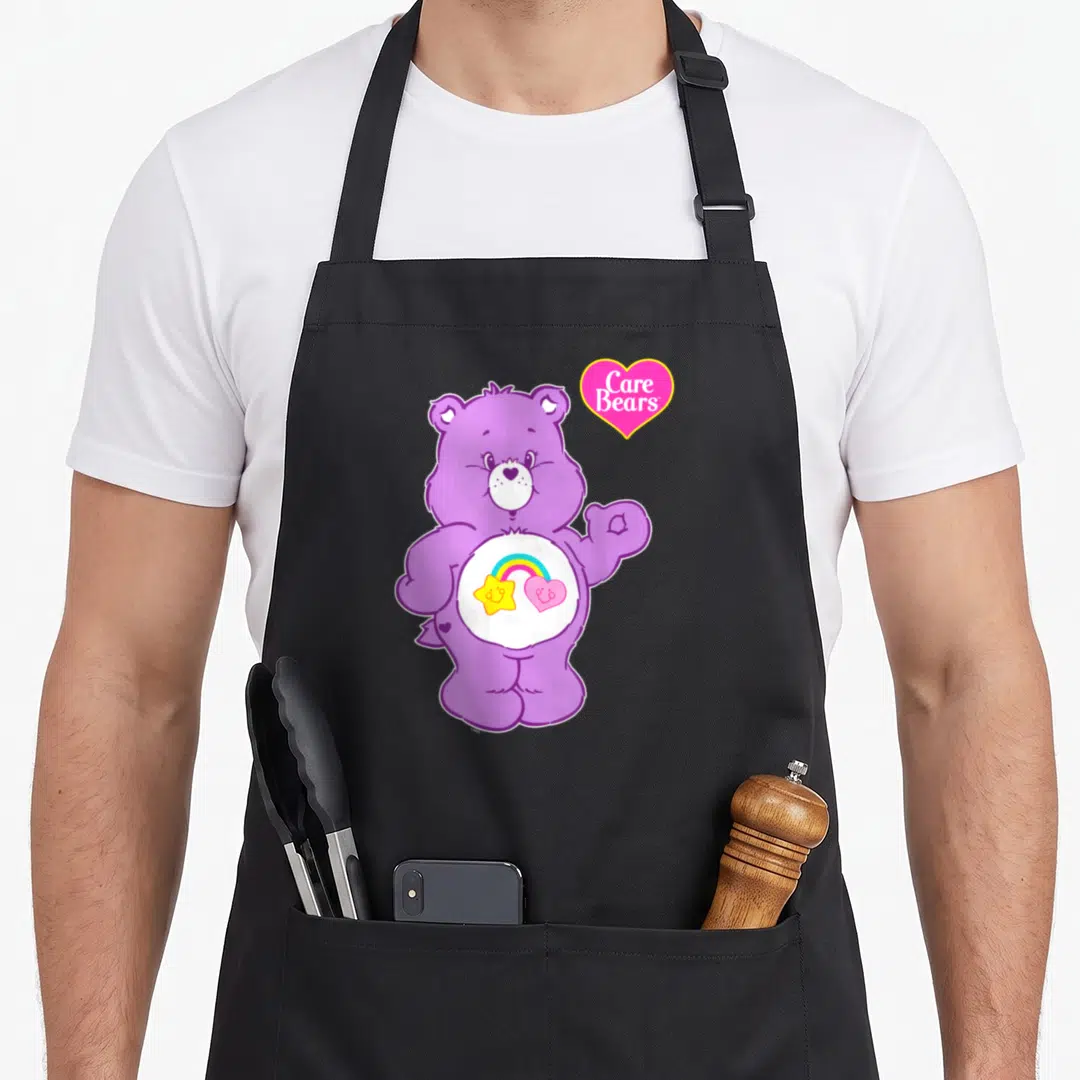 Friends apron for men - Purple bear with rainbow star heart belly badge and pink Care Bears heart logo — shown on a black cotton canvas apron against a white background