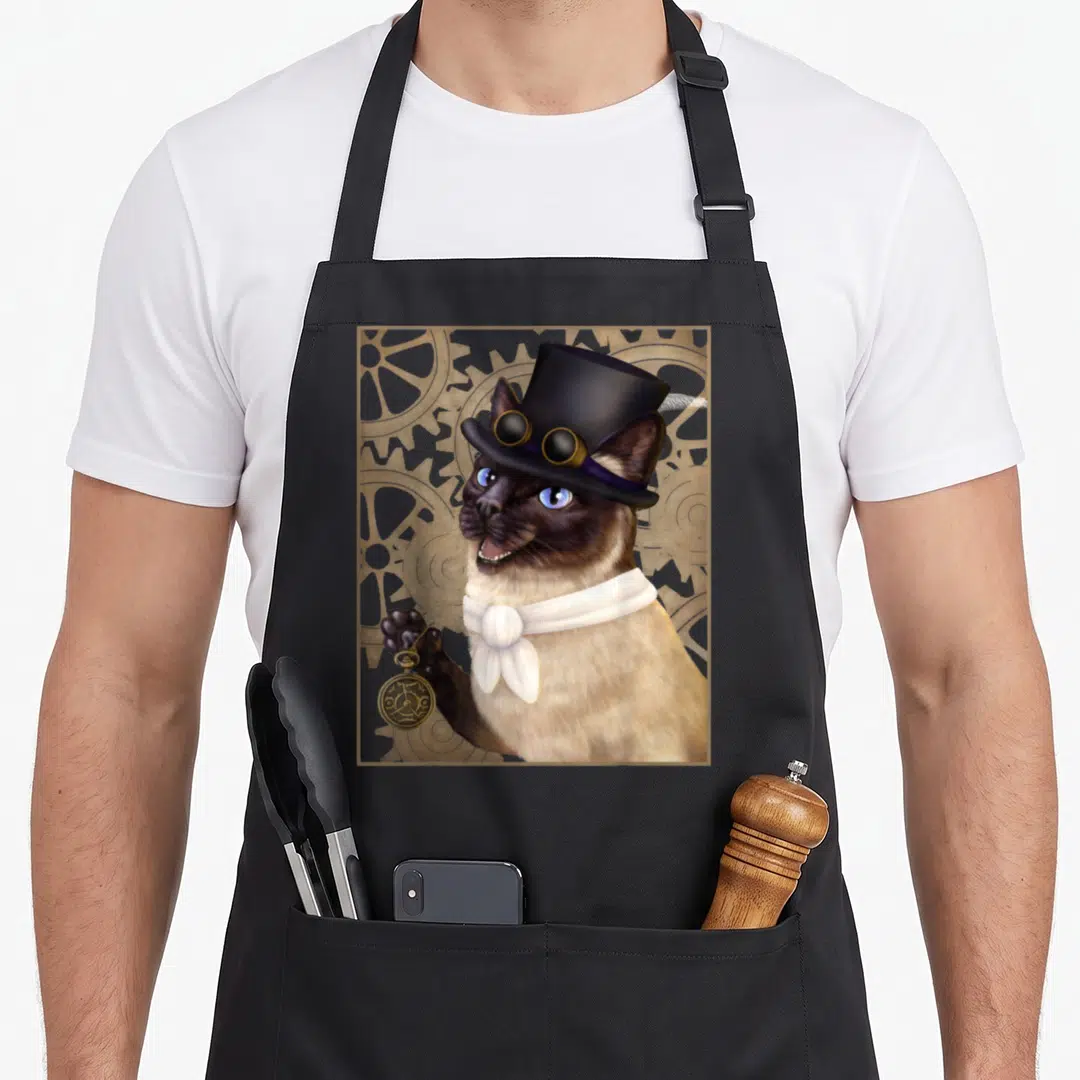 Steampunk cute cat aprons - Siamese cat in top hat and goggles holding pocket watch against gold gear background — shown on a black cotton canvas apron against a white background