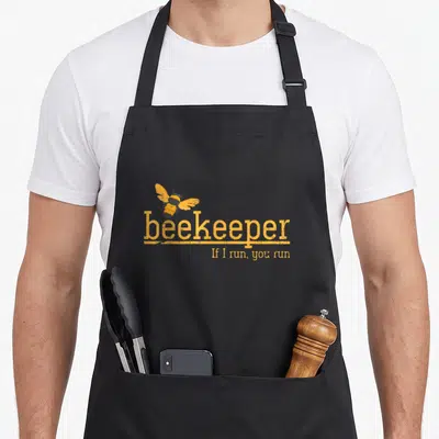 Hive honey bee apron - Yellow and black bee illustration above beekeeper text and If I run you run slogan — shown on a black cotton canvas apron against a white background