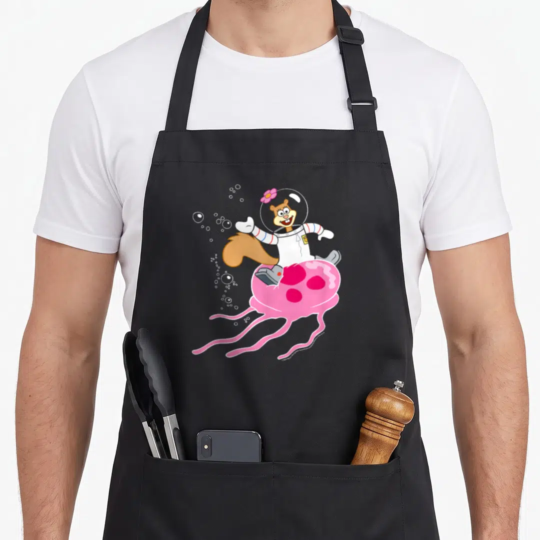 Squarepant jellyfish apron - Sandy Cheeks in spacesuit riding pink jellyfish with white bubbles — shown on a black cotton canvas apron against a white background