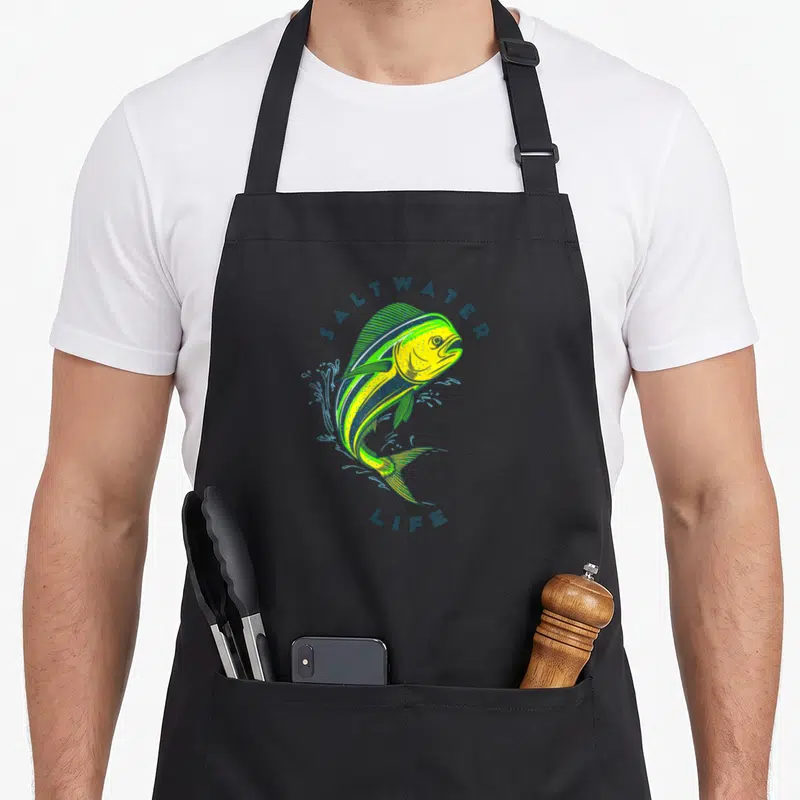 Saltwater fishing aprons - Jumping mahi mahi fish in yellow and blue with SALTWATER LIFE text — shown on a black cotton canvas apron against a white background