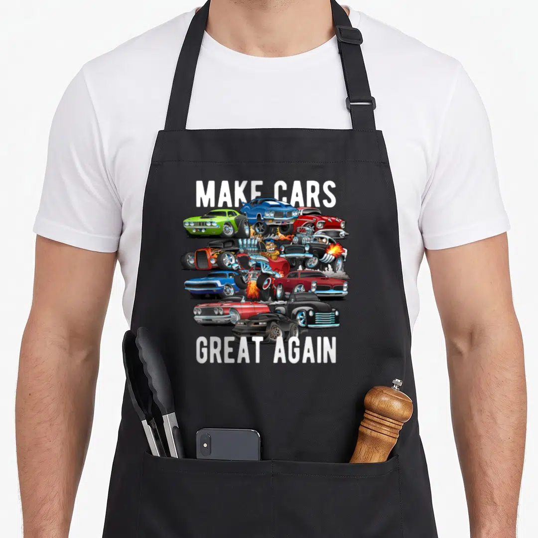 Hotrod muscle apron - Make Cars Great Again text framing cartoon hotrods and muscle cars in white blue red green — shown on a black cotton canvas apron against a white background