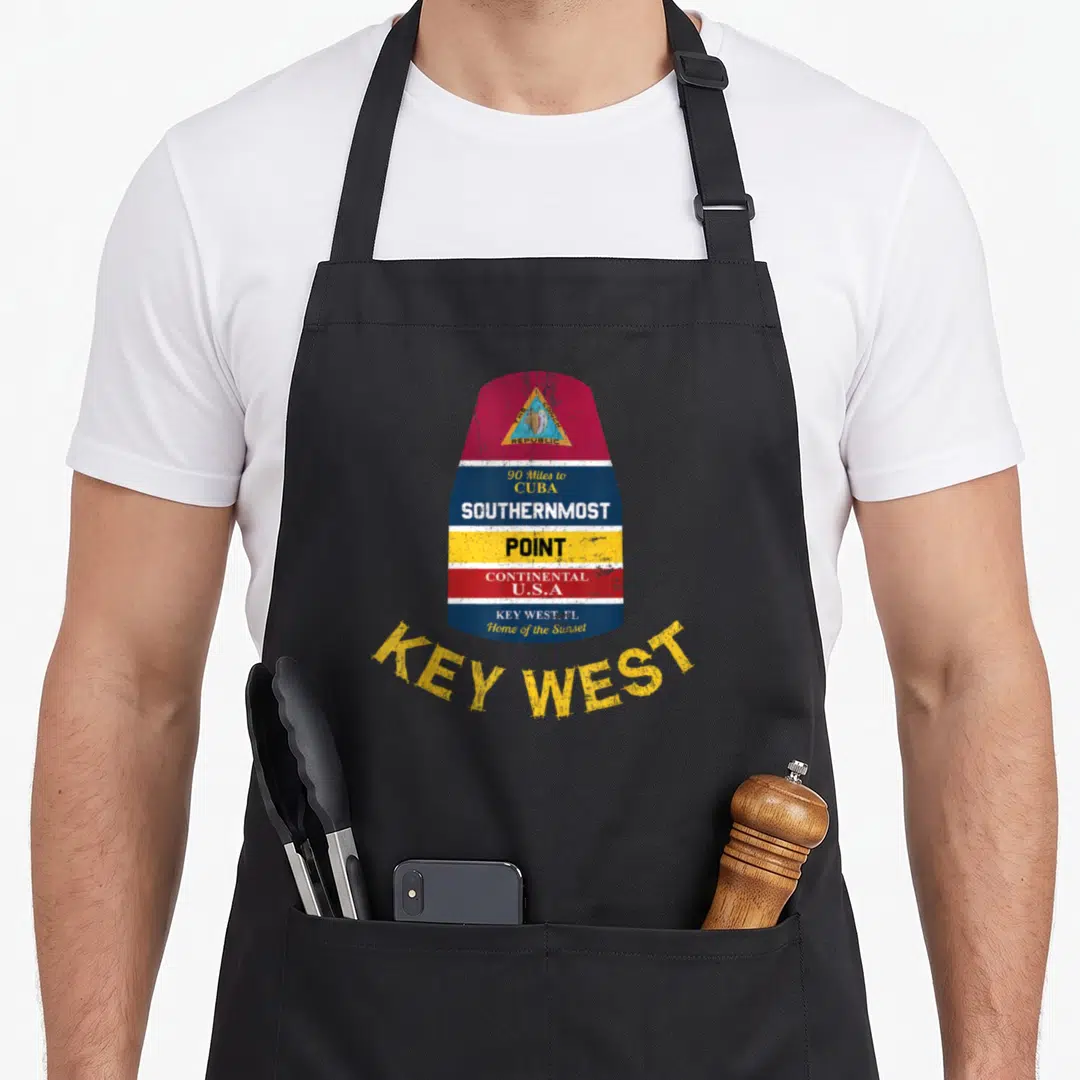Southernmost florida apron - Retro marker sign with red blue yellow white bands reading 90 Miles to CUBA SOUTHERNMOST — shown on a black cotton canvas apron against a white background