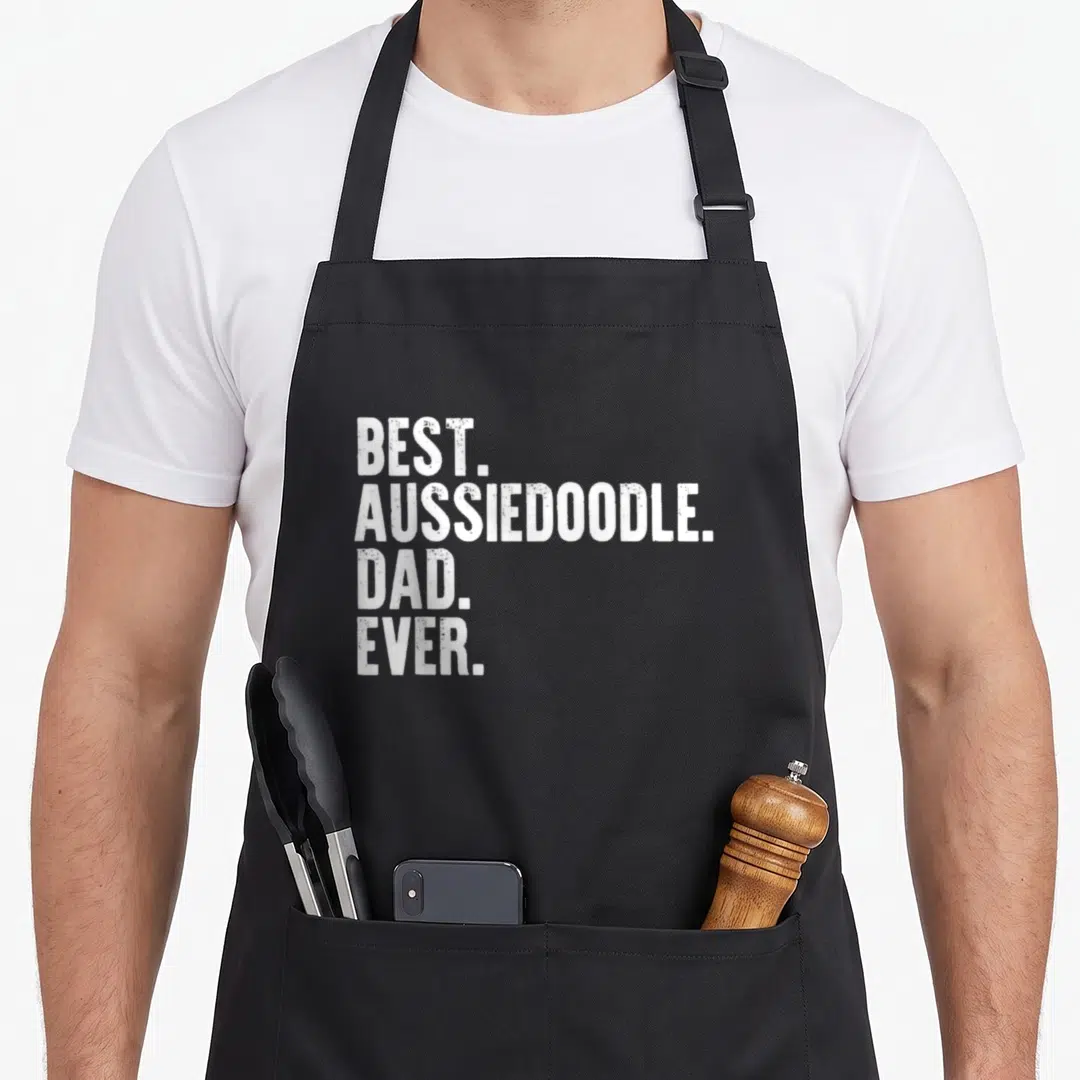Aussiedoodle father day apron - White distressed text reading BEST. AUSSIEDOODLE. DAD. EVER. stacked in four lines — shown on a black cotton canvas apron against a white background