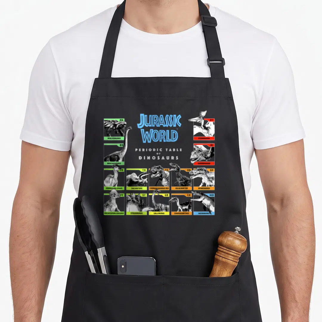 Jurassic table apron - Periodic table of dinosaurs chart with 14 species illustrations and colored borders — shown on a black cotton canvas apron against a white background