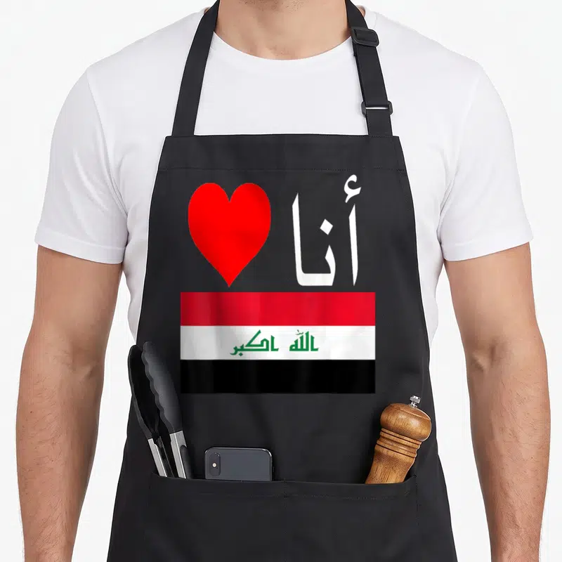 Iraq i love arab apron - Red heart and white Arabic text above red white and black Iraqi flag — shown on a black cotton canvas apron against a white background