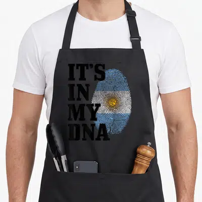 Dna argentine girl apron - Stacked text It's In My DNA next to a distressed fingerprint shaped like the Argentine flag — shown on a black cotton canvas apron against a white background