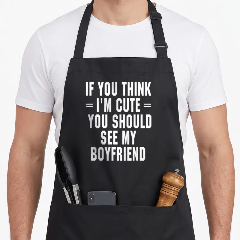 Should girlfriend funny apron - White stacked text IF YOU THINK I'M CUTE YOU SHOULD SEE MY BOYFRIEND on black background — shown on a black cotton canvas apron against a white background