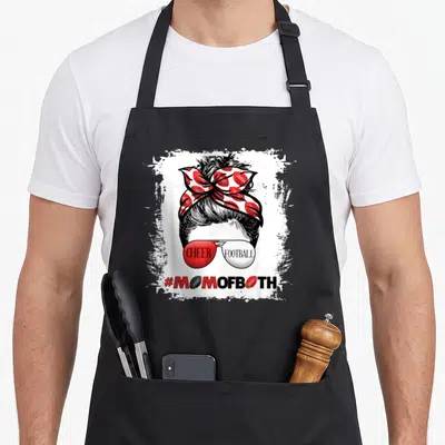 Cheer messy aprons - Cartoon woman bun with football scarf sunglasses reading cheer football mom of both — shown on a black cotton canvas apron against a white background