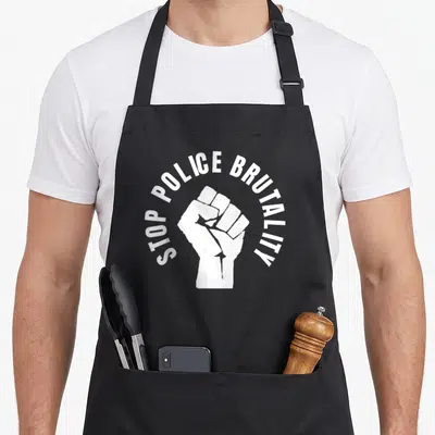 Stop police apron - White raised fist with arched text reading STOP POLICE BRUTALITY — shown on a black cotton canvas apron against a white background